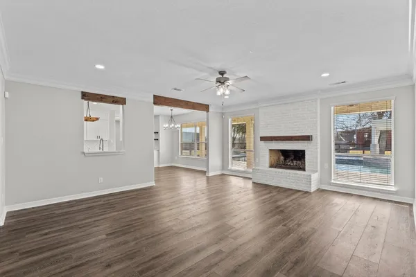 a kitchen with stainless steel appliances granite countertop a stove top oven a refrigerator and a window with wooden floors