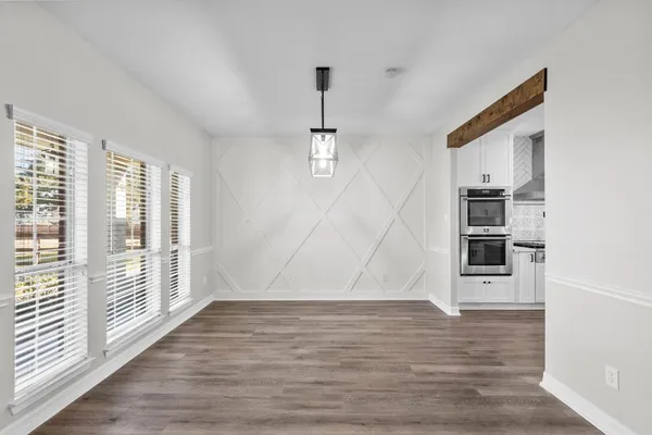 a view of an empty room with wooden floor fireplace and a window