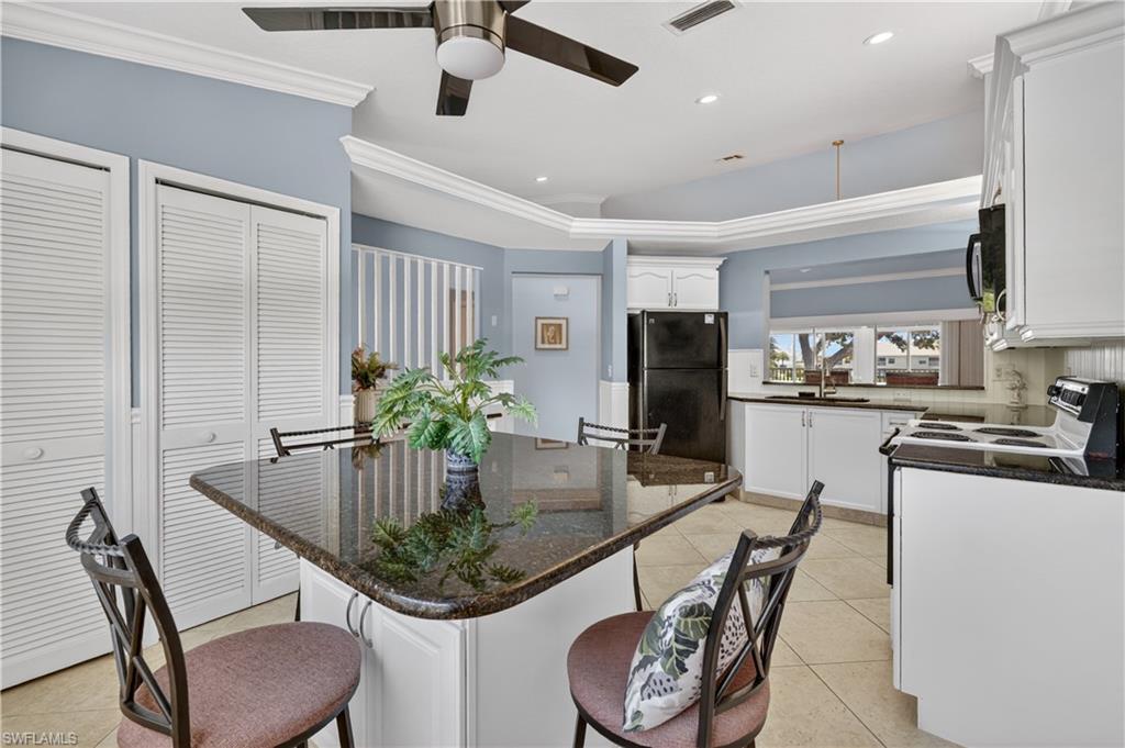 13061 Hamilton Harbour Drive, Unit R5 Naples, FL 34110 - Photo 7 of 39 a kitchen with stainless steel appliances kitchen island granite countertop a table chairs and a refrigerator
