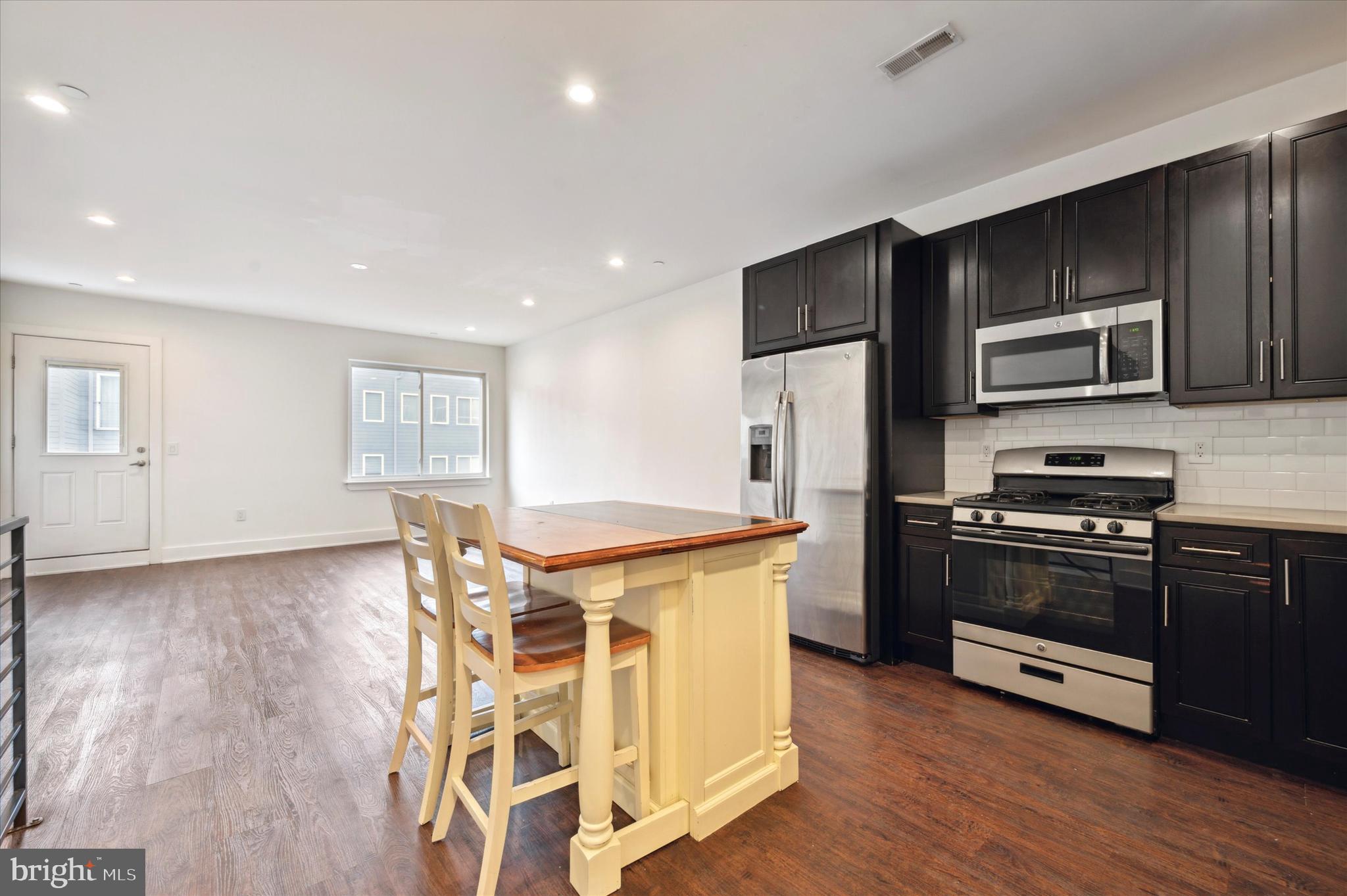 1219 North 5th Street, Unit 2 Philadelphia, PA 19122 - Photo 6 of 16 a kitchen with stainless steel appliances granite countertop a refrigerator a stove top oven a sink dishwasher and wooden floor