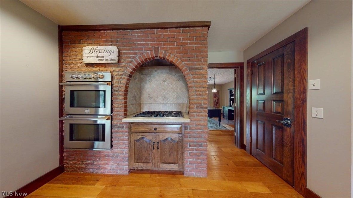 3985 Wiers Road Willard, OH 44890 - Photo 17 of 50 Brick feature wall with integrated stainless steel double ovens and an arched alcove with a built-in gas cooktop