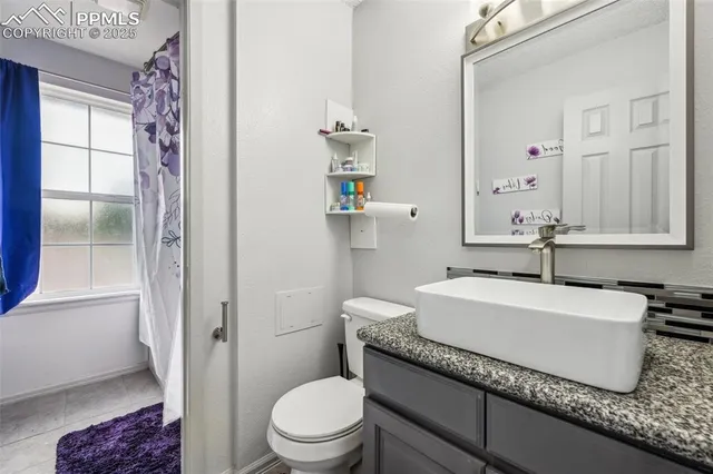 a bathroom with a granite countertop sink a toilet and a mirror