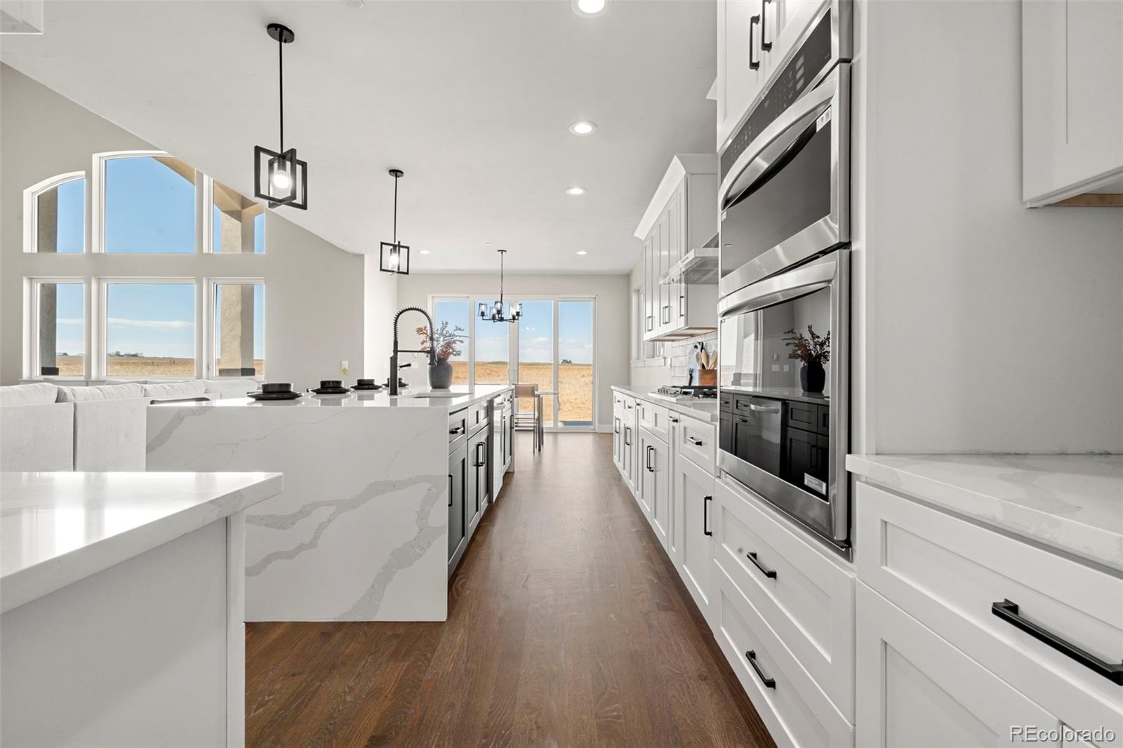 12450 Imboden Road Hudson, CO 80642 - Photo 9 of 46 a view of a kitchen with kitchen island a sink stainless steel appliances and a counter top space