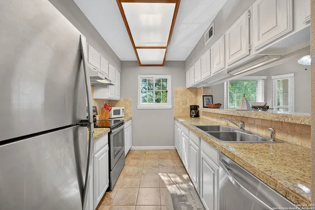 a kitchen with stainless steel appliances granite countertop a sink stove and a refrigerator