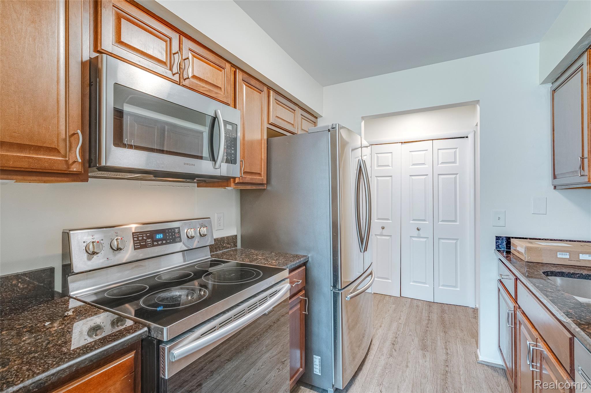 29860 West 12 Mile Road, Unit 604 Farmington, MI 48334 - Photo 6 of 26 Kitchen featuring stainless steel appliances, light wood-style flooring, wood finish cabinetry, and dark stone countertops