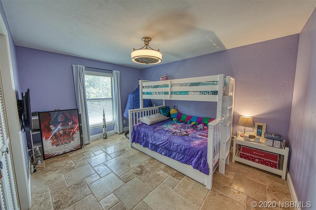 4718 South Atlantic Avenue Ponce Inlet, FL 32127 - Photo 12 of 22 a bedroom with a bed and a chandelier