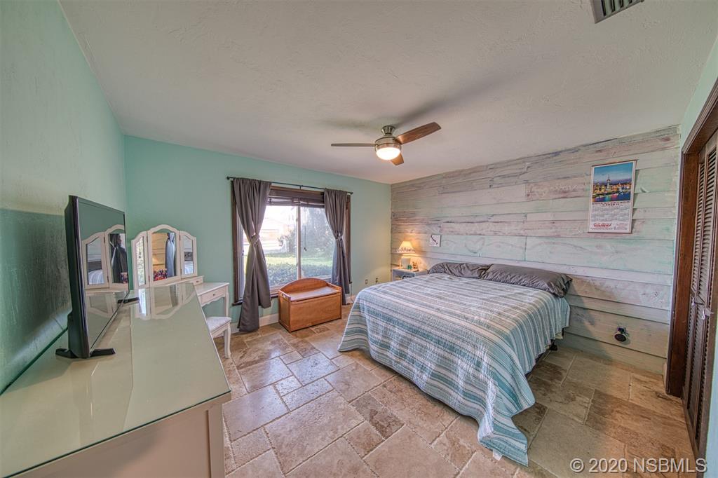 4718 South Atlantic Avenue Ponce Inlet, FL 32127 - Photo 10 of 22 a bedroom with a bed a flat screen tv and windows