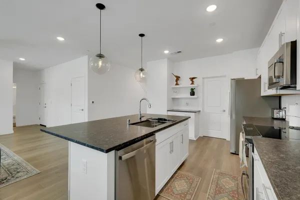 a kitchen with stainless steel appliances granite countertop a sink a stove and a refrigerator