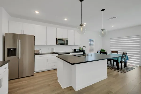 a kitchen with stainless steel appliances granite countertop a stove a sink dishwasher and a dining table with wooden floor