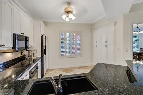 a kitchen with granite countertop a stove a sink and a refrigerator