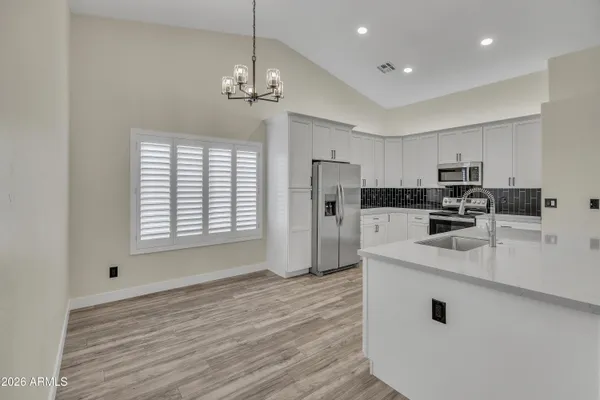 a kitchen with stainless steel appliances granite countertop a refrigerator a sink dishwasher a stove and white countertops with wooden floor