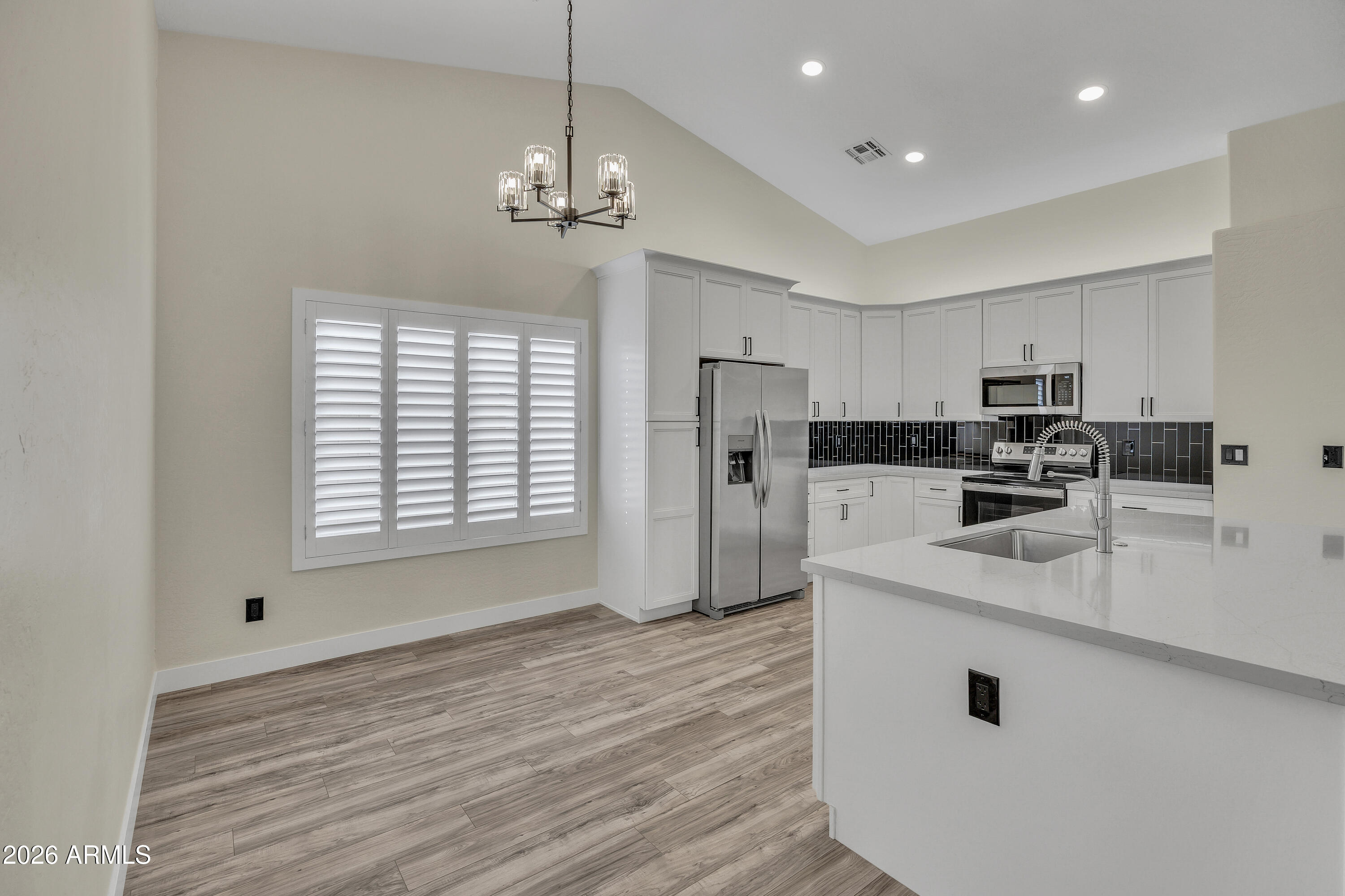 3283 East Bonanza Road Gilbert, AZ 85297 - Photo 4 of 31 a kitchen with stainless steel appliances granite countertop a refrigerator a sink dishwasher a stove and white countertops with wooden floor