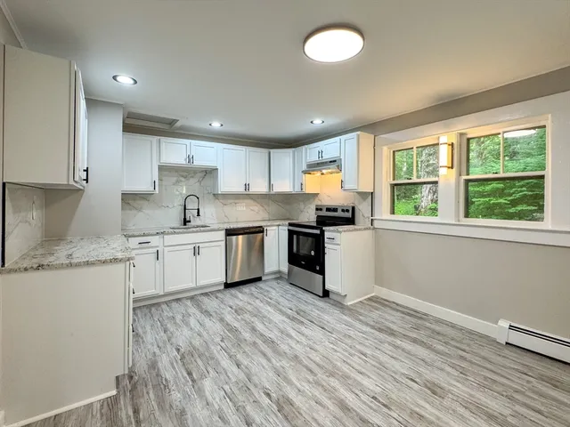a kitchen with granite countertop a stove top oven sink and cabinets