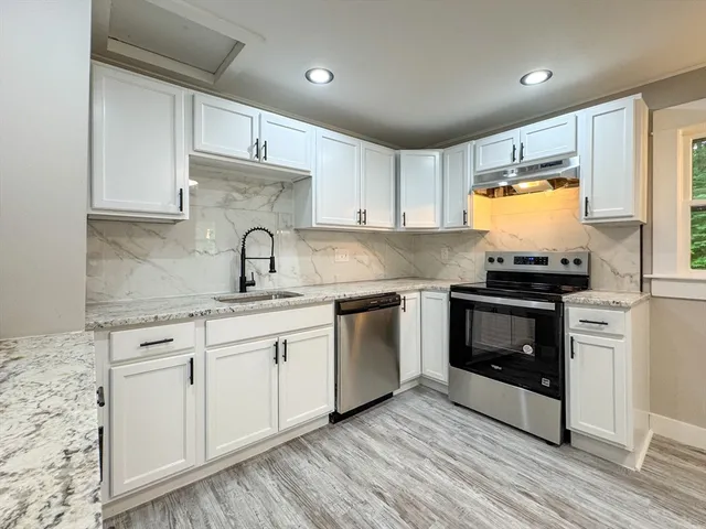 a kitchen with granite countertop white cabinets and stainless steel appliances