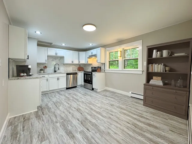 a kitchen with stainless steel appliances granite countertop a stove top oven a sink dishwasher and a refrigerator with wooden floor