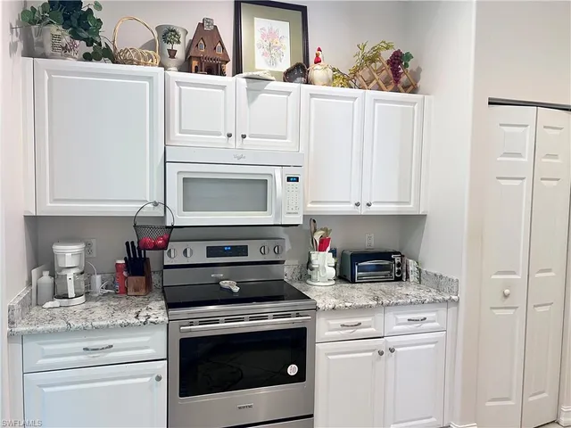 a kitchen with white cabinets and appliances