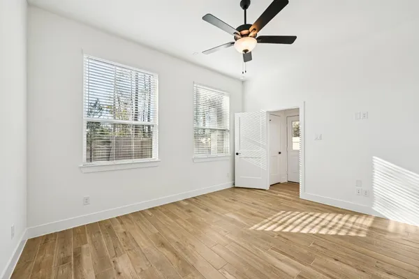an empty room with wooden floor and windows