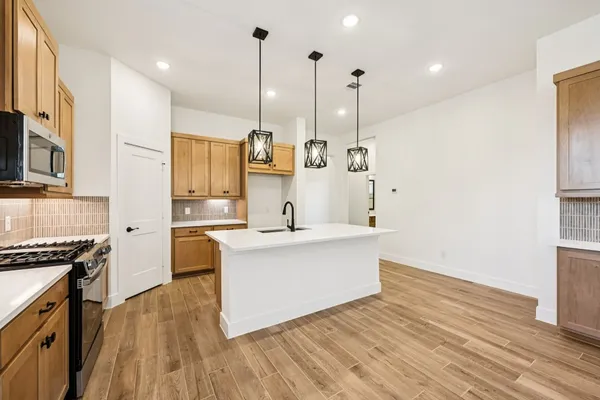 a large kitchen with stainless steel appliances kitchen island granite countertop a stove a sink and white cabinets