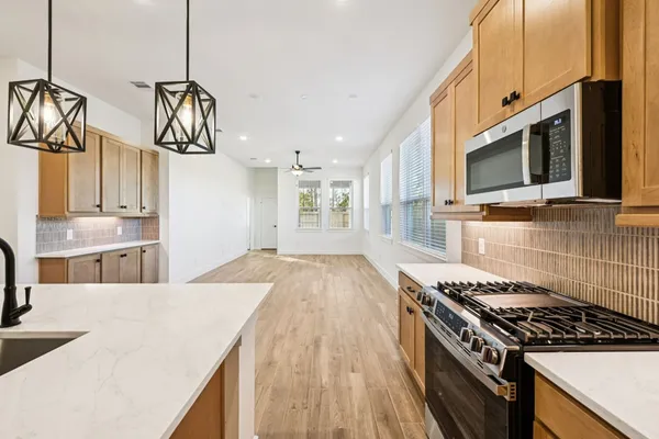 a kitchen with stainless steel appliances granite countertop a sink a stove a refrigerator and island with wooden floor