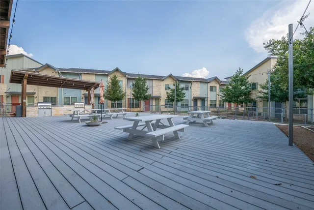 a view of a patio with dining table and chairs with wooden floor and fence