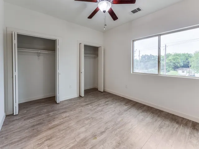 a view of an empty room with a window and wooden floor
