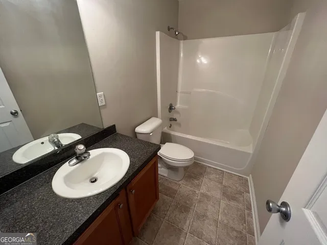 a bathroom with a sink a toilet a mirror and shower