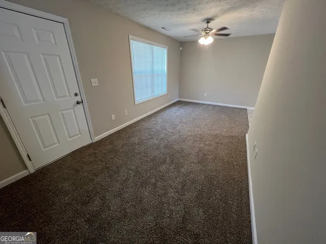 an empty room with a ceiling fan and a window