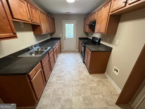 a kitchen with granite countertop a sink stove and cabinets