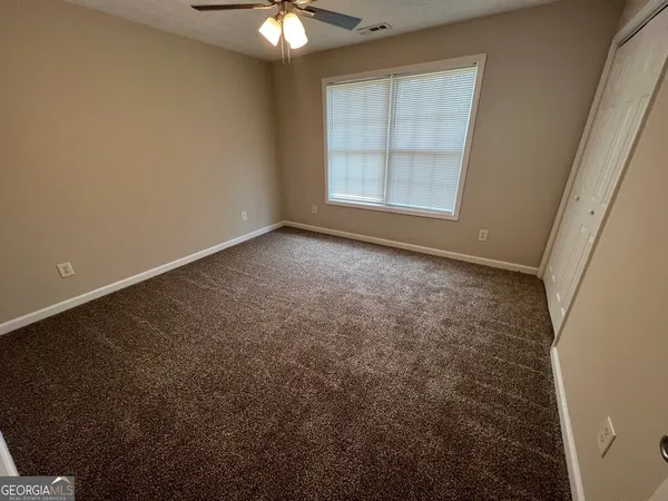 an empty room with windows and fan