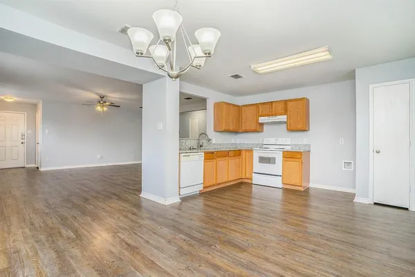 a view of a kitchen center island wooden floor and stainless steel appliances
