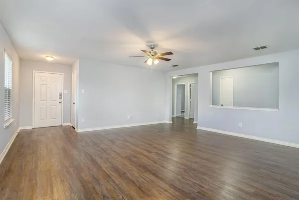 a view of an empty room with window and wooden floor