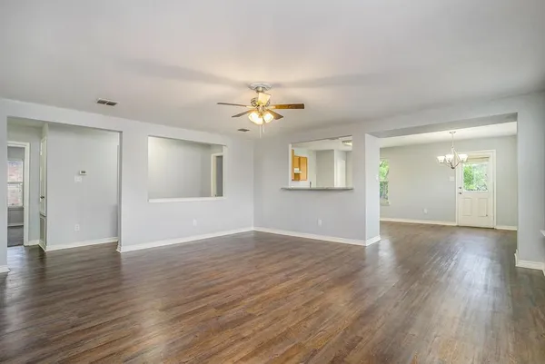 an empty room with wooden floor and a ceiling fan