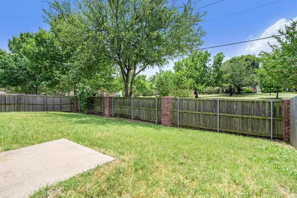 a view of a backyard with a fence and trees
