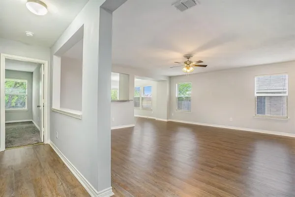 a view of an empty room with wooden floor and a window