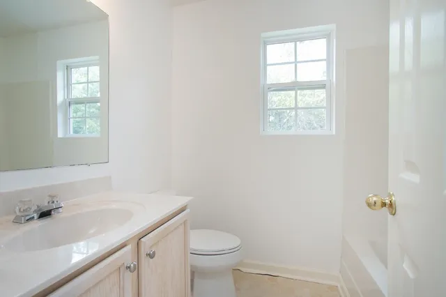 a bathroom with a granite countertop sink a toilet and a window