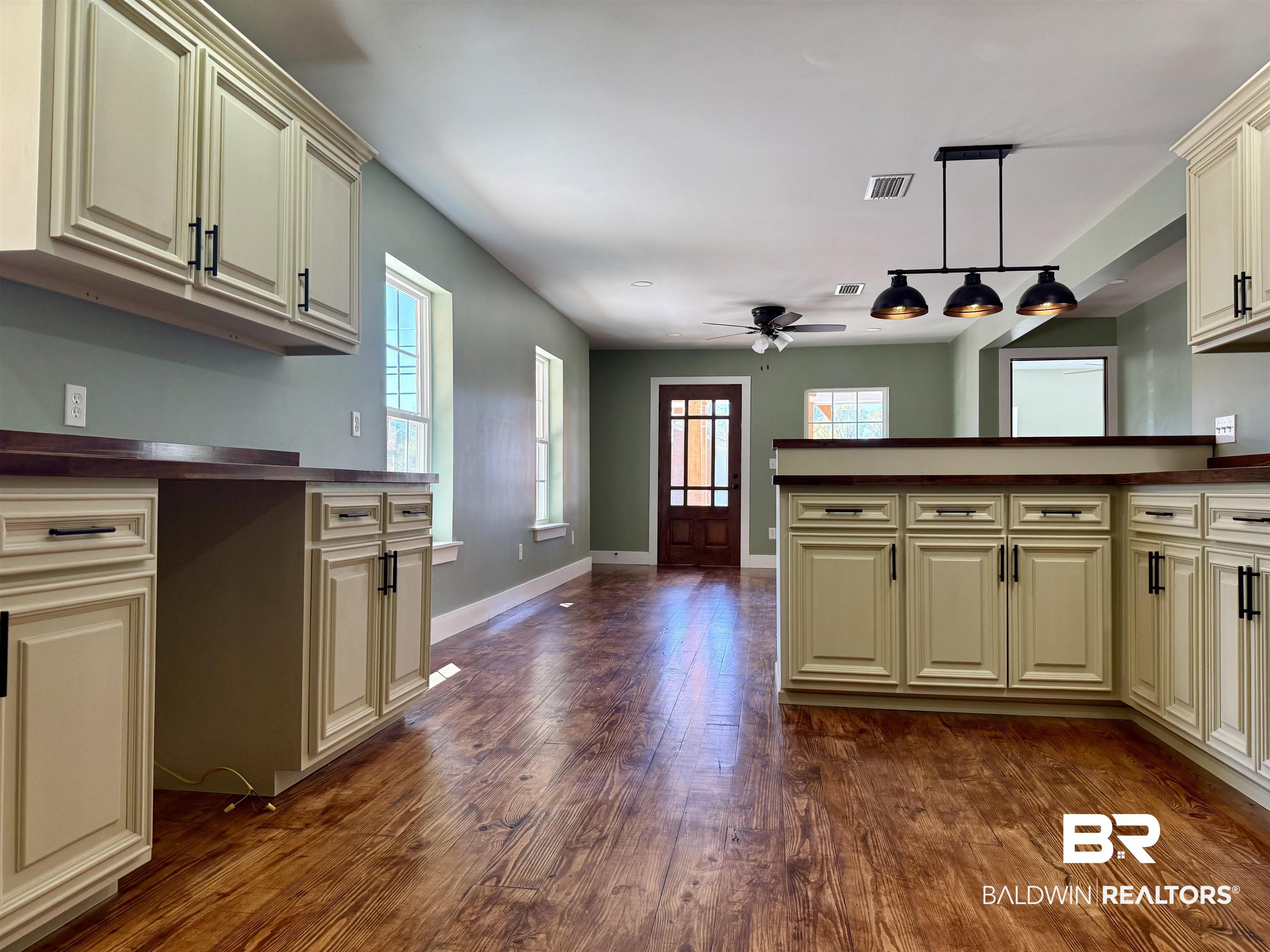 613 Forrest Avenue Brewton, AL 36426 - Photo 6 of 22 Kitchen with dark countertops, cream cabinets, dark wood finished floors, hanging light fixtures, and plenty of natural light