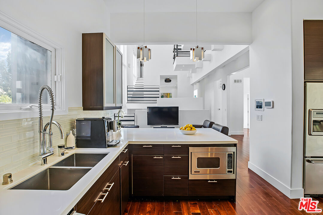 1857 North Beverly Drive Beverly Hills, CA 90210 - Photo 20 of 49 a kitchen with stainless steel appliances a stove a sink and a microwave