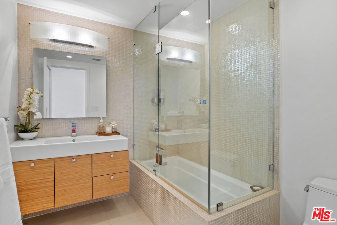 1857 North Beverly Drive Beverly Hills, CA 90210 - Photo 36 of 49 a bathroom with a tub sink shower and mirror