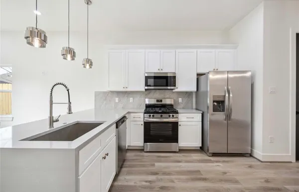 a kitchen with stainless steel appliances granite countertop a sink a stove a refrigerator and cabinets