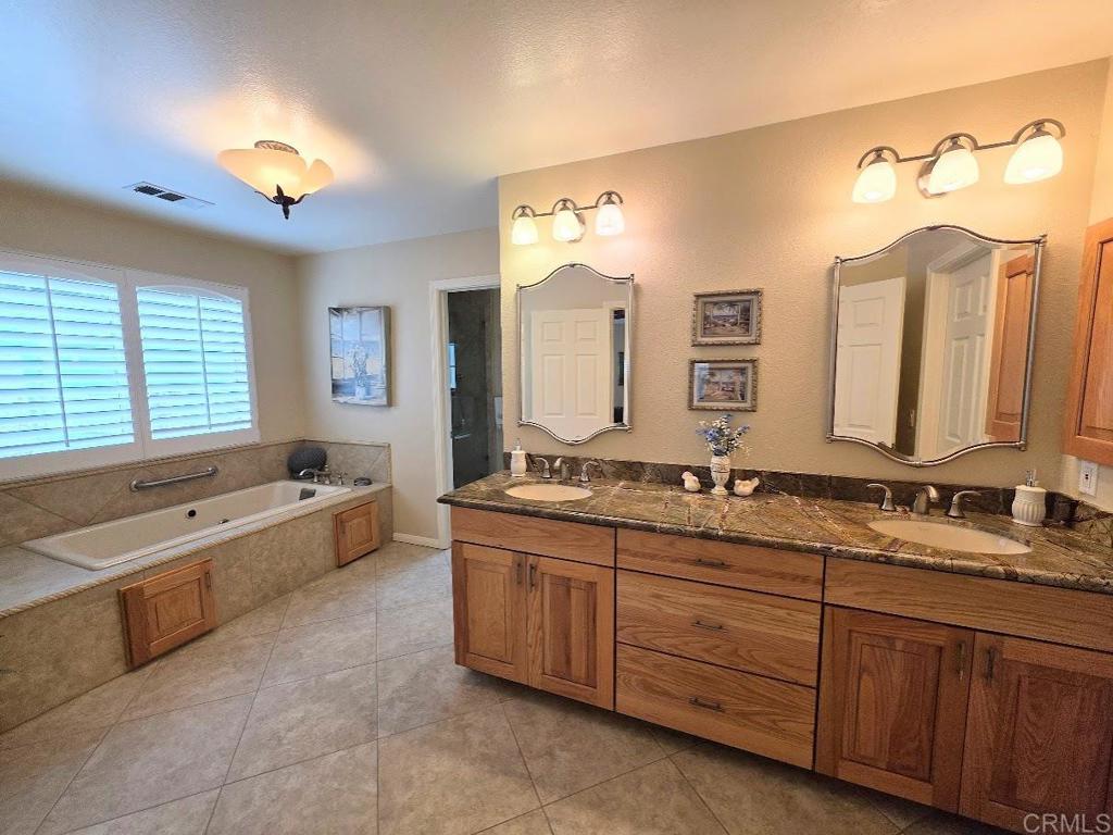25084 Pappas Road Ramona, CA 92065 - Photo 20 of 58 a spacious bathroom with a double vanity sink large mirror and a bathtub