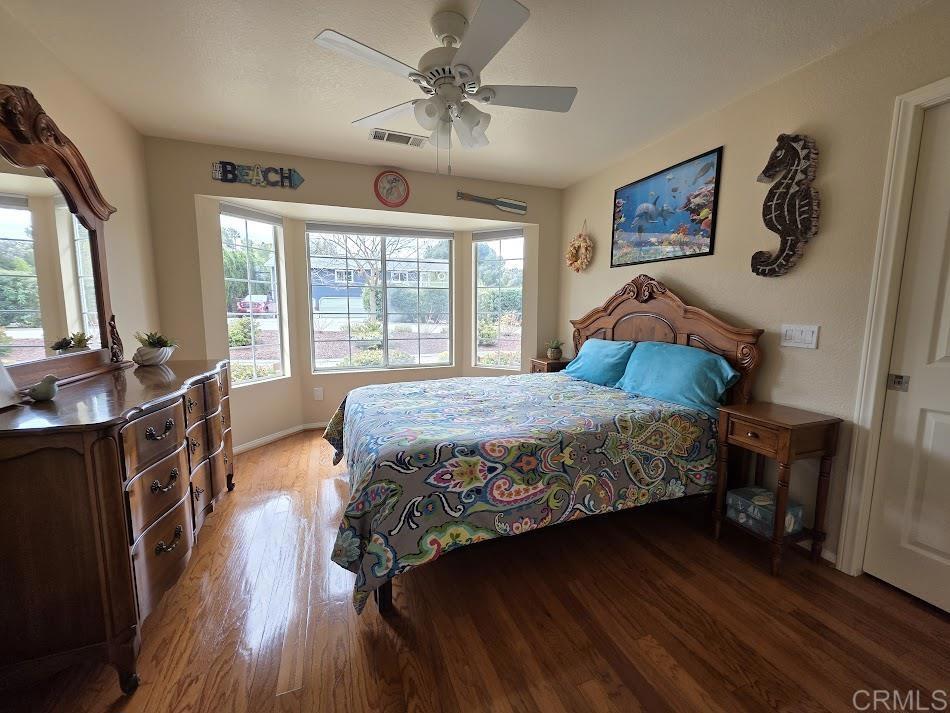 25084 Pappas Road Ramona, CA 92065 - Photo 22 of 58 a bedroom with a large bed a large window with wooden floor
