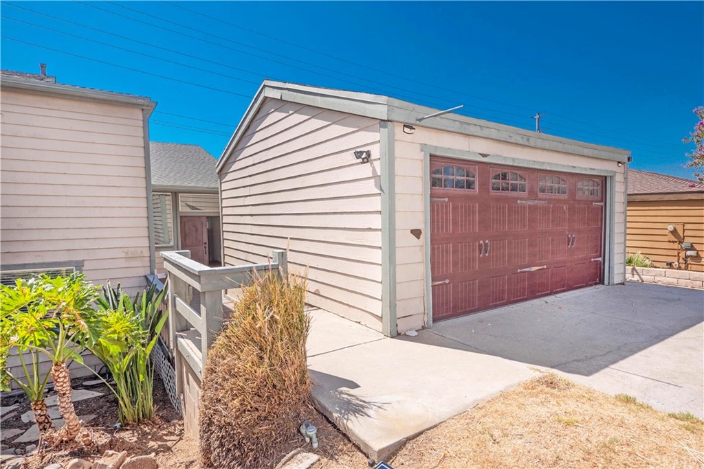 home is set behind detached garage, double door entry is at the end of walkway