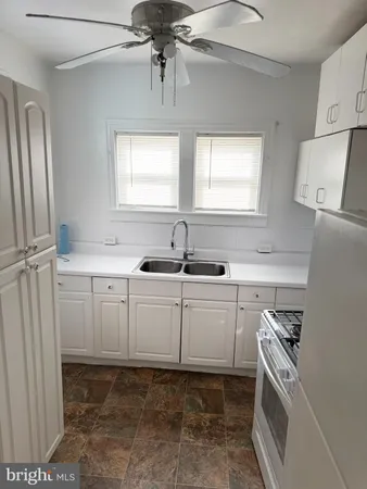 a kitchen with white cabinets and sink