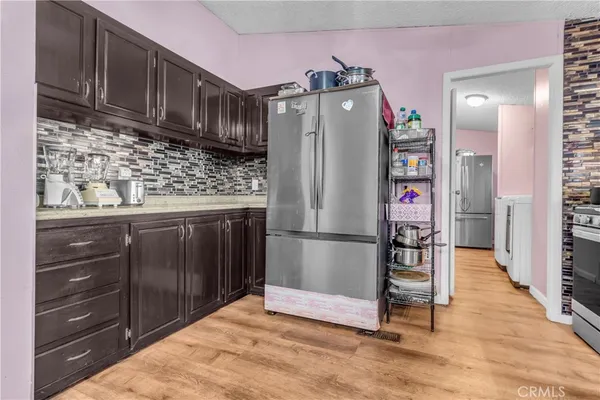 a kitchen with granite countertop a refrigerator and a wooden cabinets