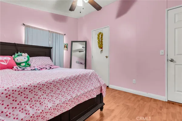 a bedroom with a bed and a dresser with wooden floor