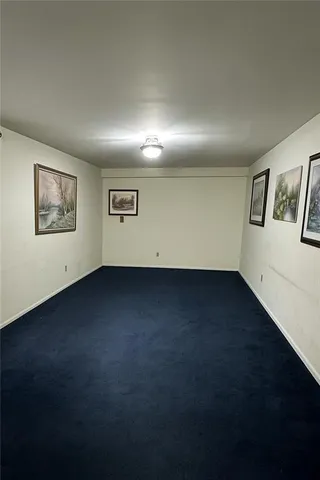 a view of an empty room with wooden floor and fan