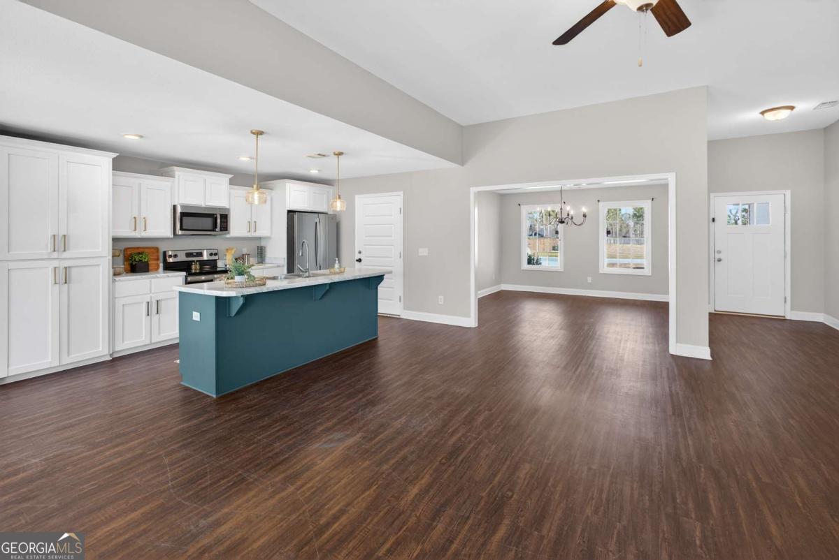 303 Tallulah Bend Ellabell, GA 31308 - Photo 11 of 48 a kitchen with stainless steel appliances kitchen island wooden floors refrigerator and cabinets