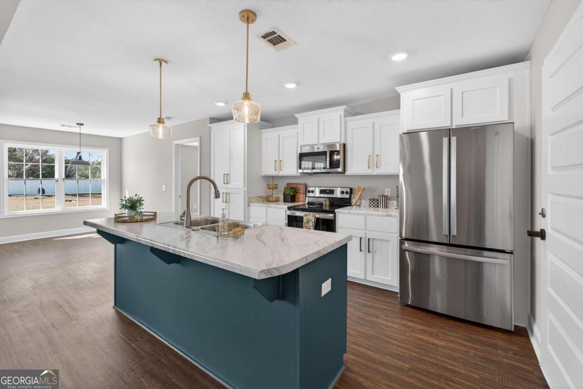 303 Tallulah Bend Ellabell, GA 31308 - Photo 18 of 48 a kitchen with kitchen island a sink appliances a counter space and a center island