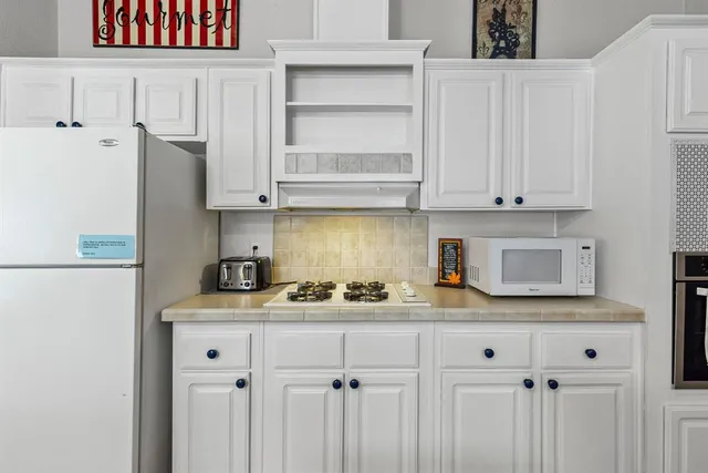 a kitchen with stainless steel appliances granite countertop a sink a refrigerator and a white cabinets