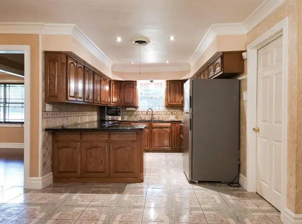 a kitchen with stainless steel appliances granite countertop a refrigerator a sink dishwasher a stove with wooden cabinets and floor